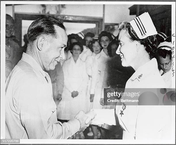 The first navy nurse to be presented with the bronze star medal, Lieutenant Commander Faye E. White USN, receives a firm handshake from vice admiral...