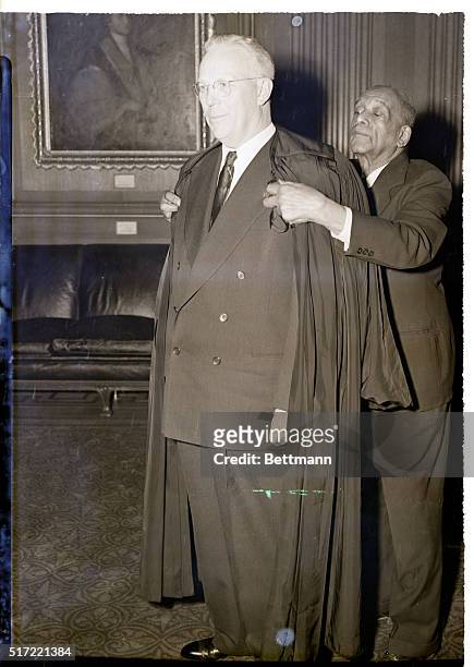 Washington, DC- Former Governor, Earl Warren, who was sworn in October 5th as Chief Justce of the US, is helped on with his robe by R.H. Marshall,...