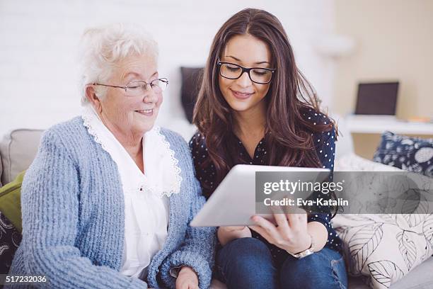 granddaughter together with her happy grandmother at home - happy ipad beautiful stockfoto's en -beelden