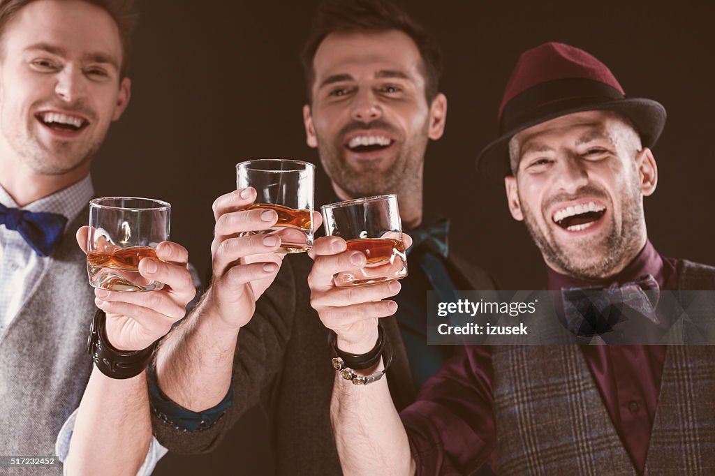 Happy elegant men toasting with whiskey