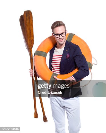 Confident blonde young man holding lifebuoy and paddle Confident blonde young man holding lifebuoy and paddle