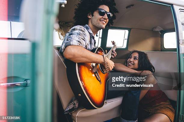 hipster young adult man plays guitar for his girlfriend - car passion stock pictures, royalty-free photos & images