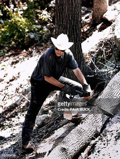 President George W. Bush uses a chainsaw to cut up a dead Hackberry tree in a canyon on his ranch 25 August 2001 near Crawford, Texas. Bush is...