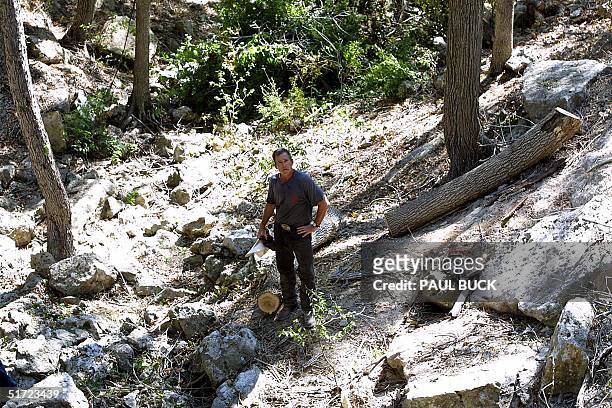 President George W. Bush stands at the bottom of a canyon where he uses a chainsaw to cut up a dead Hackberry tree on his ranch near Crawford, Texas,...