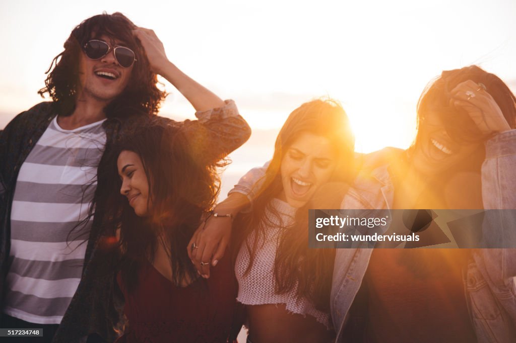 Friends cheering and hugging on summertime at sunset