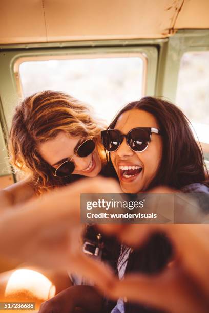 two hipster girls posing for photo making hand heart - groups of 12 year old school children stockfoto's en -beelden