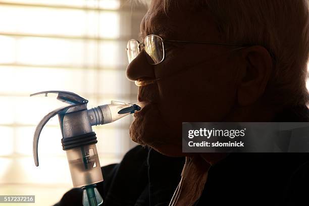 hombre de edad avanzada con nebulizador - nebulizador fotografías e imágenes de stock