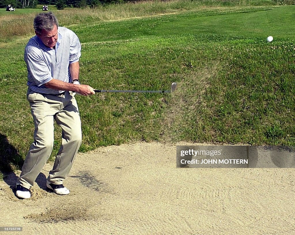 US President George W. Bush chips out of a sand tr