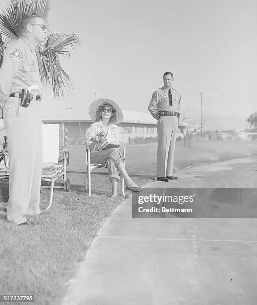 Rita Hayworth, attired in blue jeans, relaxes on the grounds of the Sands Hotel in Las Vegas under the watchful eyes of Deputy Sheriff Bill Grover...