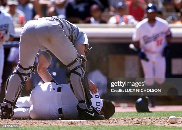 Seattle Mariners' catcher Tom Lampkin bends over Los Angeles Dodgers' Paul Lo Duca as he lies on the ground after being hit in the face by a pitch...