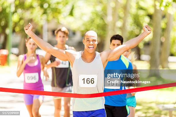 male marathon runner crossing finishing line - marathon winner stock pictures, royalty-free photos & images