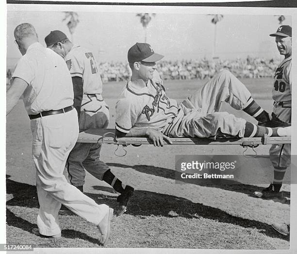 Outfielder Bobby Thomson of the Milwaukee Braves is carried off the field after suffering a triple fracture into second base in an exhibition game...
