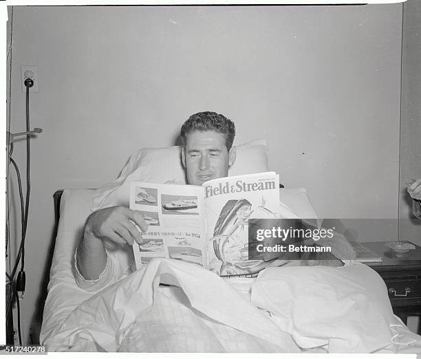 Boston Red Sox star, Ted Williams, recuperating from a shoulder operation in Santa Maria Hospital in Cambridge, Mass., laughs as he's caught reading...