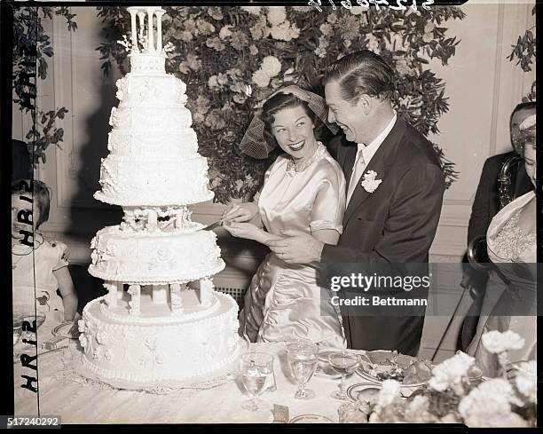 New York, NY- Milton Berle's bride, the former Ruth Cosgrove cuts their huge wedding cake with the help of her new spouse after the ceremony 12/9....