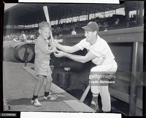 This photo shows little Michael "Corky" Cronin son of the Red Sox Manager, Joe Cronin, as Ted Williams, terrific thumper, shows him how to hold his...