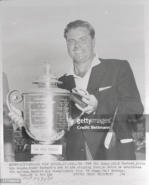 The 1954 PGA champion, Chick Harbert, smiles proudly as he holds the trophy he won by defeating Walt Burkemo in the contest at Keller Golf Course in...