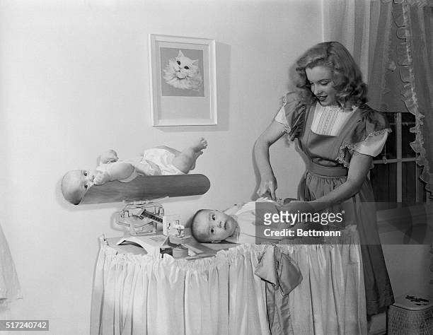 As contented a pair of babies as one would hope to see. And why not with cute 18-year-old Marilyn Monroe, as their baby sitter!" Marilyn was saving...