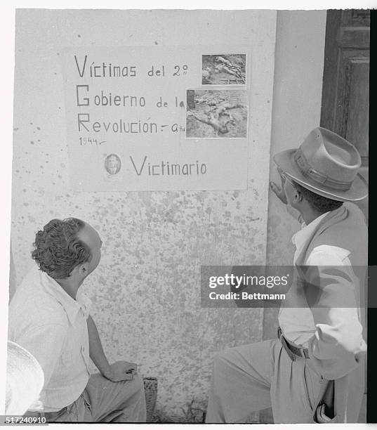 At Villanueva, eight miles from Guatemala City, two men look at posted photographs of bodies of atrocity victims found on the outskirts of the...