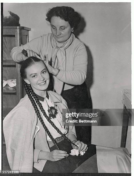 Lovely Janette Scott, who wears her own long hair in Braids for the role of Cassandra in the film Helen of Troy, lets a hairdresser add finishing...