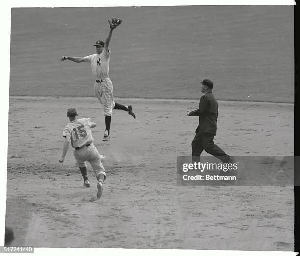 Despite Yankee catcher Yogi Berra's attempt to throw the ball into the center field bleachers, New York second baseman Gerry Coleman goes skyward to...