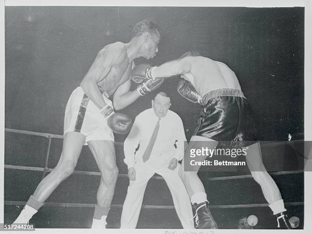 World Featherweight Champion Sandy Saddler and European Champion Ray Famechon mix it up as the referee watches during their scheduled ten-round...