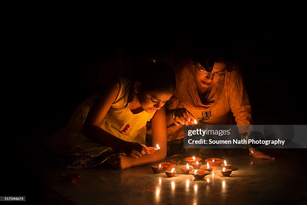 Mother and daughter lighting diyas on Diwali