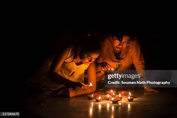 mother and daughter lighting diyas on diwali - diya oil lamp stock pictures, royalty-free photos & images