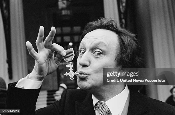 English comedian and singer Ken Dodd pictured holding his OBE following an investiture at Buckingham Palace in London on 19th February 1982.