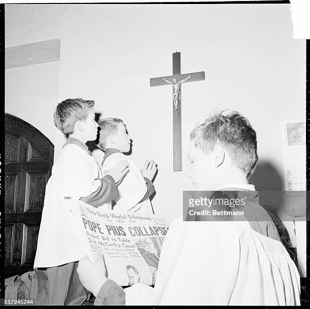 Altar boys David James Wood and John Joseph Newman Pray for Pope Pius XII as john sammit holds a newspaper announcing the collapse of the Pontiff....