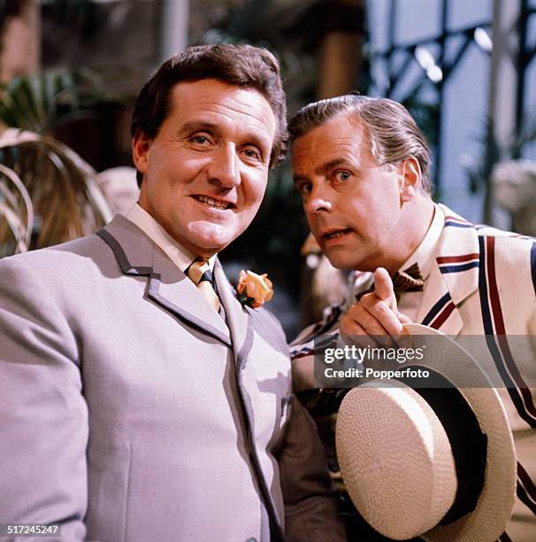 English actors Patrick Macnee and Ian Carmichael wearing a boating blazer and holding a boater, pictured together in character as Algernon Moncrieff...