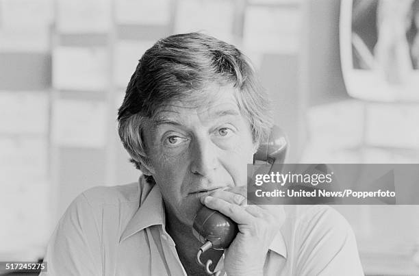 English broadcaster and author Michael Parkinson pictured holding a telephone receiver in his office in London on 27th August 1980.