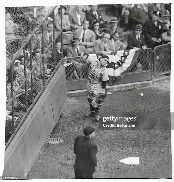 To the amusement of the fans seated behind him, Yankee catcher Yogi Berra, looking much like an adagio dancer, is shown missing Brown's foul ball in...