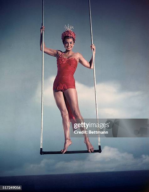 Esther William smiles as she swings from trapeze.