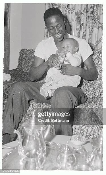 Milwaukee slugger Hank Aaron, waiting to tackle the Yanks in the World Series, relaxes at his home here, September 26th, with his son, Hank Jr. Aaron...