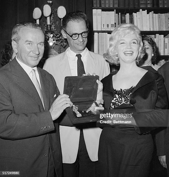 Smiling happily actress Marilyn Monroe receives Italy's David Di Donatello Award as best foreign actress of 1958 from Dr. Filippo Donini , director...