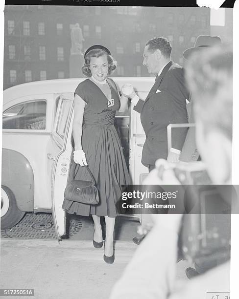 Former swimming star Eleanor Holm Rose, wearing a black silk dress, flashes a smile for the photographers as she steps out of a cab at Manhattan's...