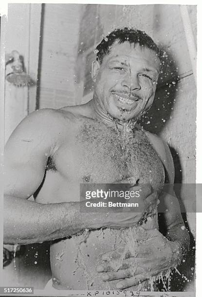 The new light-heavyweight Champion of the World, Archie Moore, enjoys a victory shower here after defeating Joey Maxim by a unanimous decision in...