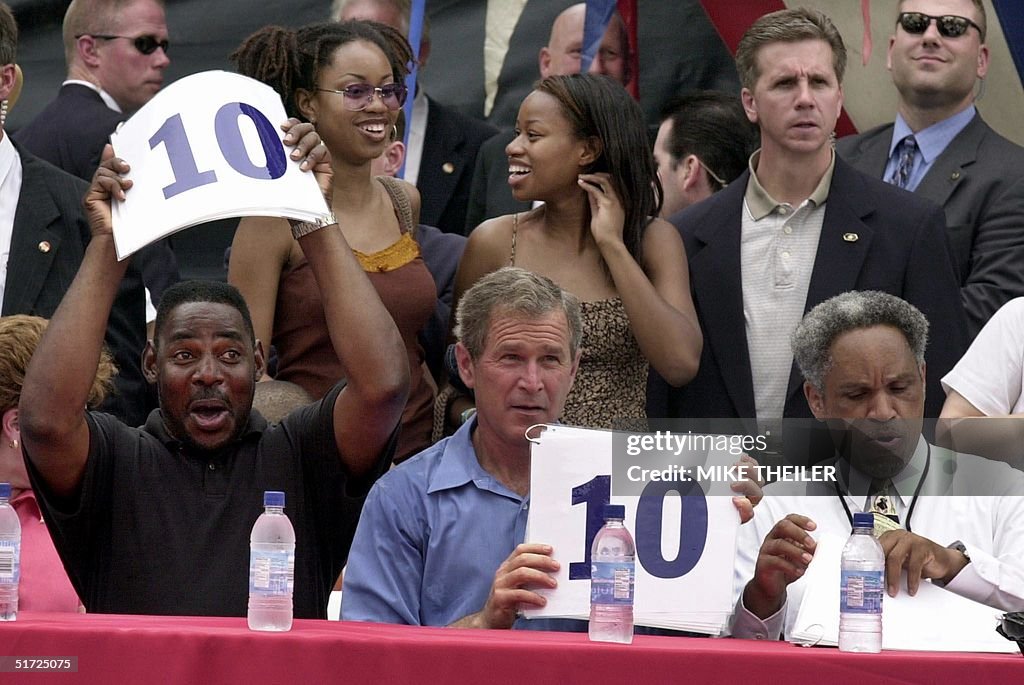 US President George W. Bush (C) holds up a "10" as