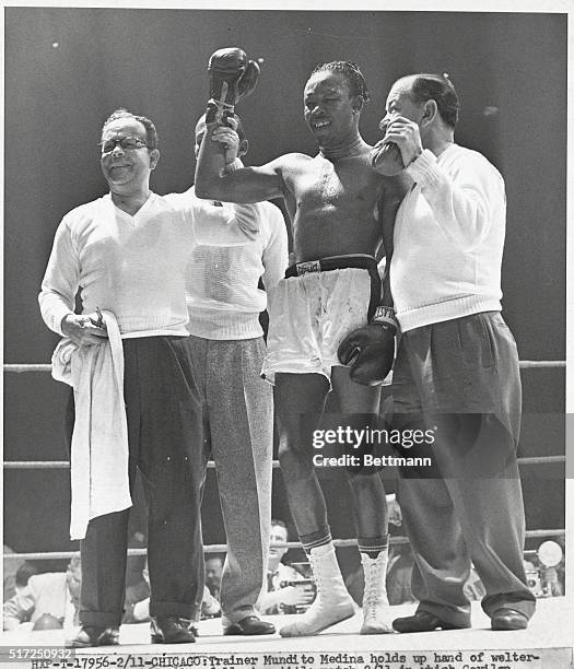 Chicago: Trainer Mundito Medina holds up hand of welterweight champ Kid Gavilan following title match 2/11, in which Gavilan defeated Chuck Davey to...