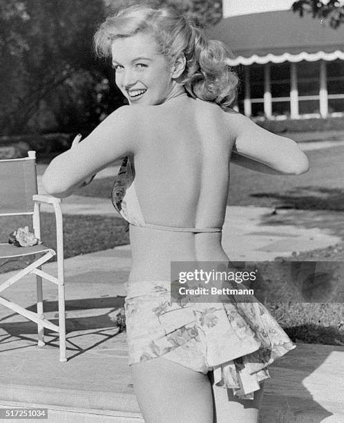 Young Marilyn Monroe, about 21, in a bikini at a swimming pool.