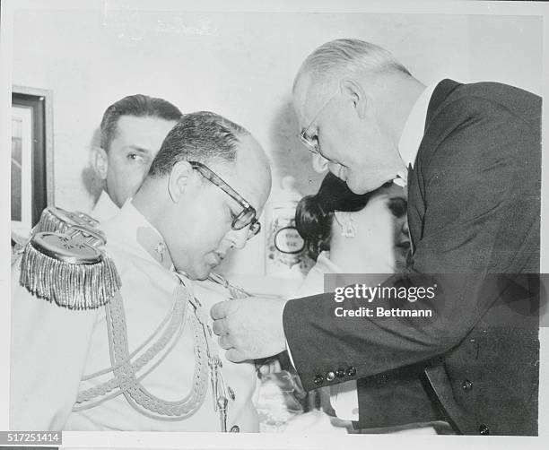 Col. Marcos Perez Jimenez, the President of Venezuela, watches closely as he is presented with the Legion of Merit, the highest military decoration...