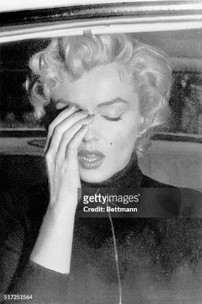 Marilyn Monroe seems to be brushing away a tear in this picture taken through a window of an automobile October 6 outside the Beverly Hills mansion...