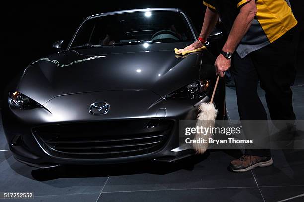 Man dusts the Mazda MX-5 RF before its introduction at the New York International Auto Show at the Javits Center on March 24, 2016 in New York City....