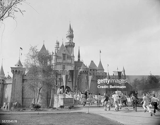 Hollywood celebrities and their children helped to make the huge opening day crowd at Disneyland. Here, a large group of them rush into Sleeping...