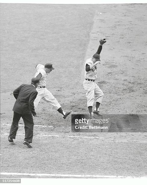 Yankee outfielder Mickey Mantle is safe at first base as Cleveland pitcher Bob Lemon, covering the bag, has to leap high in the air to snare the...