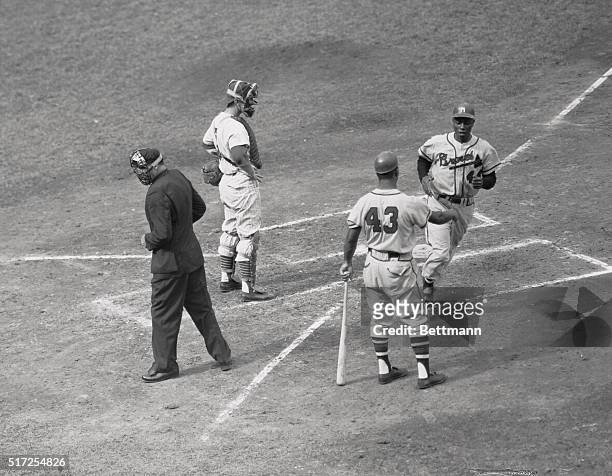 Hank Aaron of the Braves is greeted at home plate by teammate Wes Covington after clouting a home run into the right filed stands in the 4th inning...
