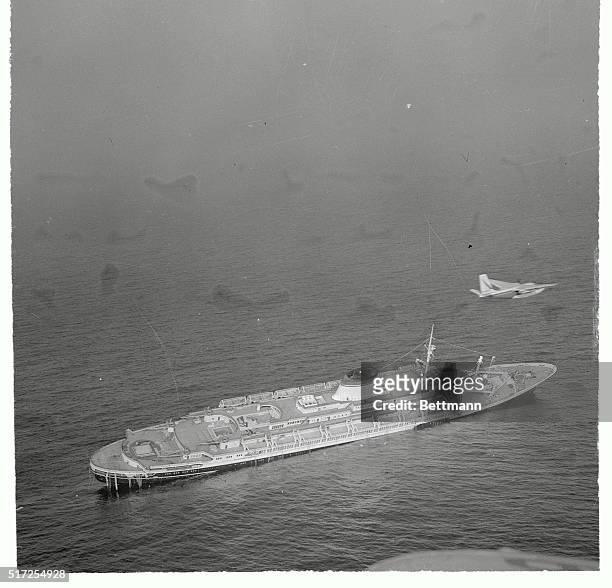 Life boats still remain on her port side as the Italian liner Andrea Doria lies dead in the water, her crew and passengers abandon, after a collision...