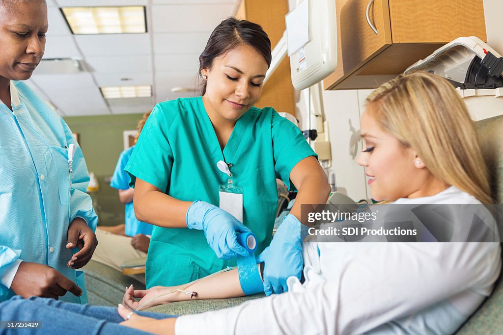 Nurse bandaging arm of patient after she donates blood