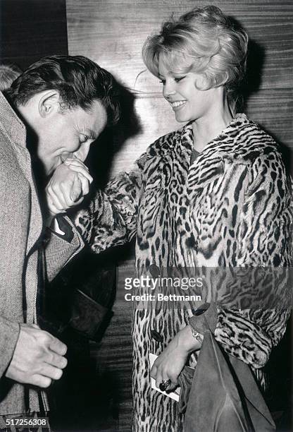 Clad in a jazzy leopard skin coat, shapely French actress Brigitte Bardot has her hand kissed in the old-fashioned style by actor Gerard Philipe....