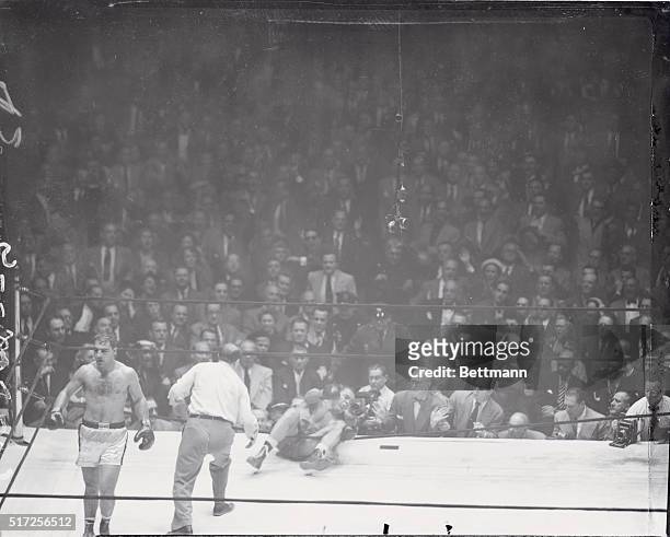 Rocky Marciano heads for his corner as Referee Ruby Goldstein heads for fallen ex-heavyweight champ Joe Louis, who was knocked through the ropes for...